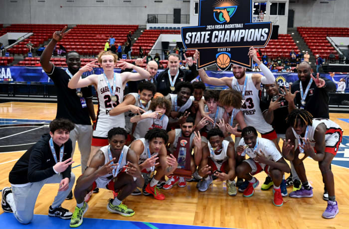 Sagemont basketball players gather around their trophy after winning their second consecutive Class 2A state championship on Thursday at the RP Funding Center in Lakeland.